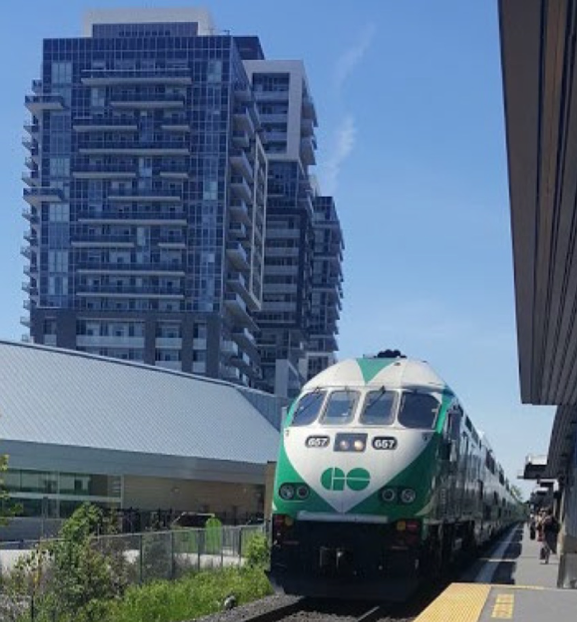 Go train parked at station with condo building behind