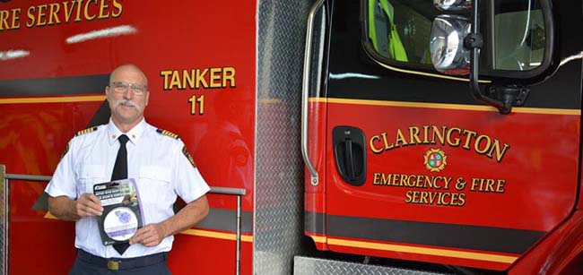 Clarington's Fire Chief holding the combination smoke and carbon monoxide alarm 