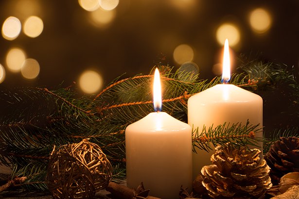 Candles burning near Christmas garland and other Christmas decorations.