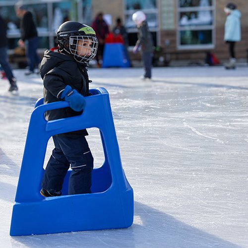 Little child using a skate aid at the outdoor rink at Courtice Community Complex.