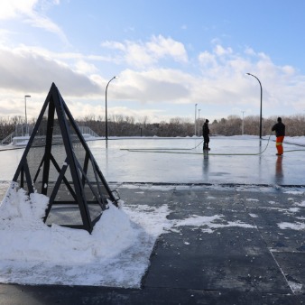 Workers fill the Diane Hamre Recreation Complex outdoor ice rink with water.