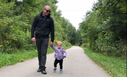 Father and toddler daughter walking