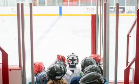 Group of youth dressed in hockey gear getting on the ice.