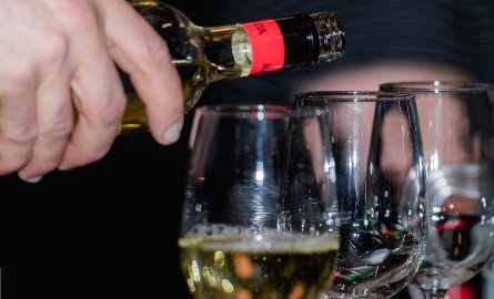 Close up of someone pouring wine into glasses.
