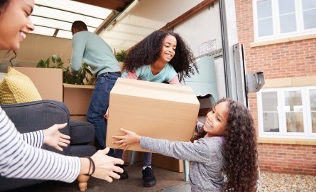 Family unloading furniture from moving van into new home