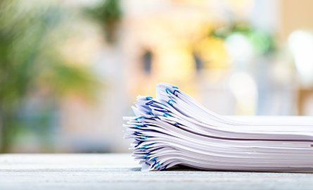 A big stack of documents on a bright interior room background