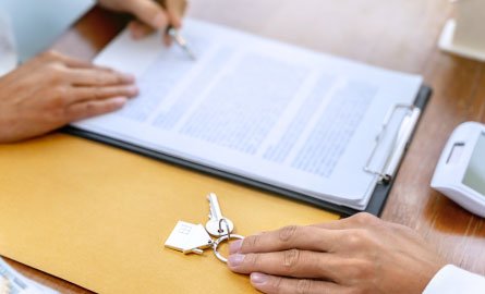 A two people reviewing a contract and handing over keys.