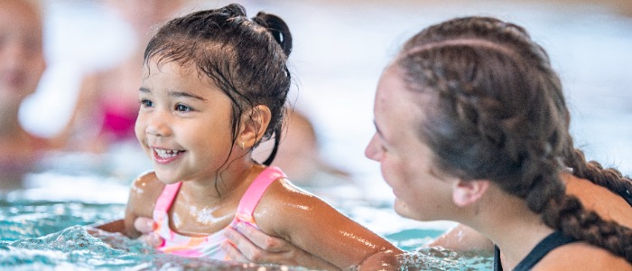 Swim instructor teaching a small child to swim.