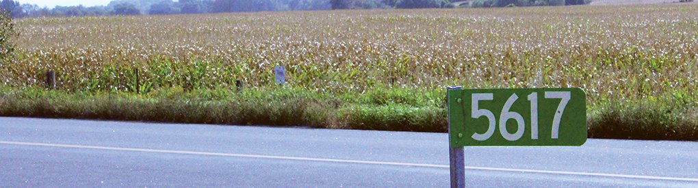 Farmer's field with green address road sign