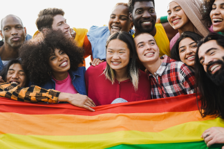 Crowd of multiracial people having fun together with pride flag.