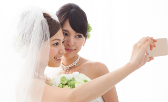 Two brides taking a selfie on their wedding day.