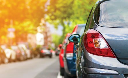 Row of cars parked on the side of the road from behind.