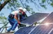 Two workers installing solar panels on a roof.