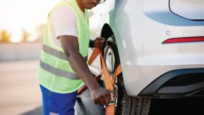 Tow truck driver securing car to tow truck.