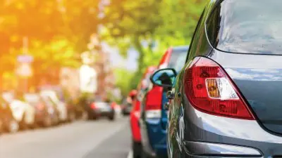 Row of cars parked on the side of the road from behind.