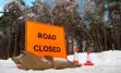 A road closure sign blocking the way on a snowy street.