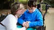 A mother and child using a wheelchair in the park.