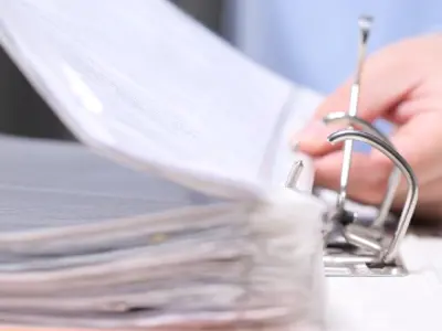 Close up of a person adding pages into a large binder.