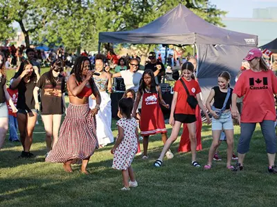 Singer from City Soul singing and teaching a dance to party goers on the park lawn