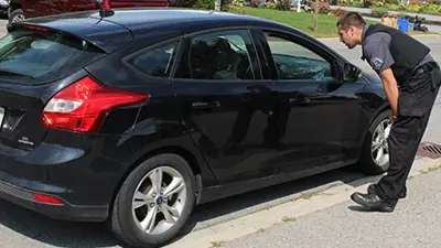 A by-law officer talking to a driver inside a car