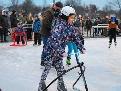 A young child uses a skate aid on the new ice rink.