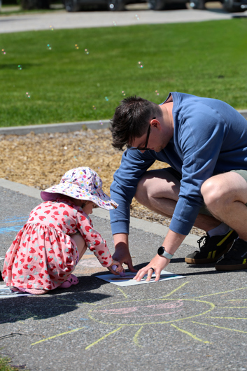 a man and a little girl drawing on the sidewalk